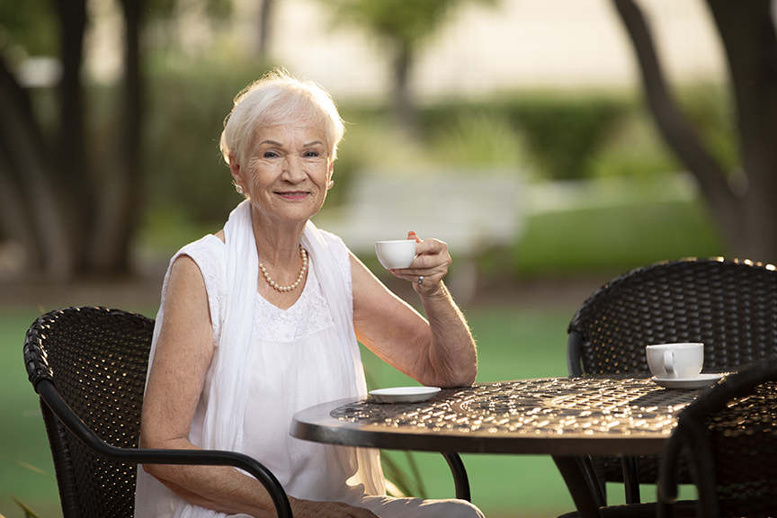 senior woman sitting outside on a patio drinking tea